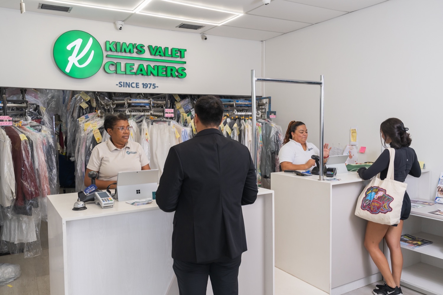 Staff helping customers at the Kim's Valet Cleaners counter on Biscayne Blvd